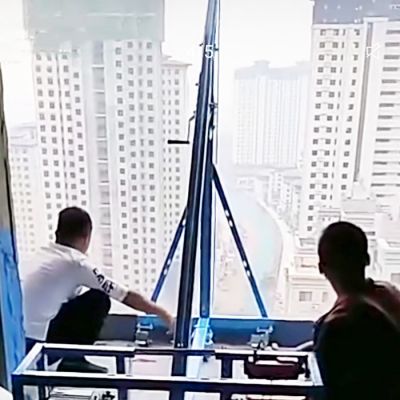 工人悠闲的使用高层吊玻璃机吊玻璃